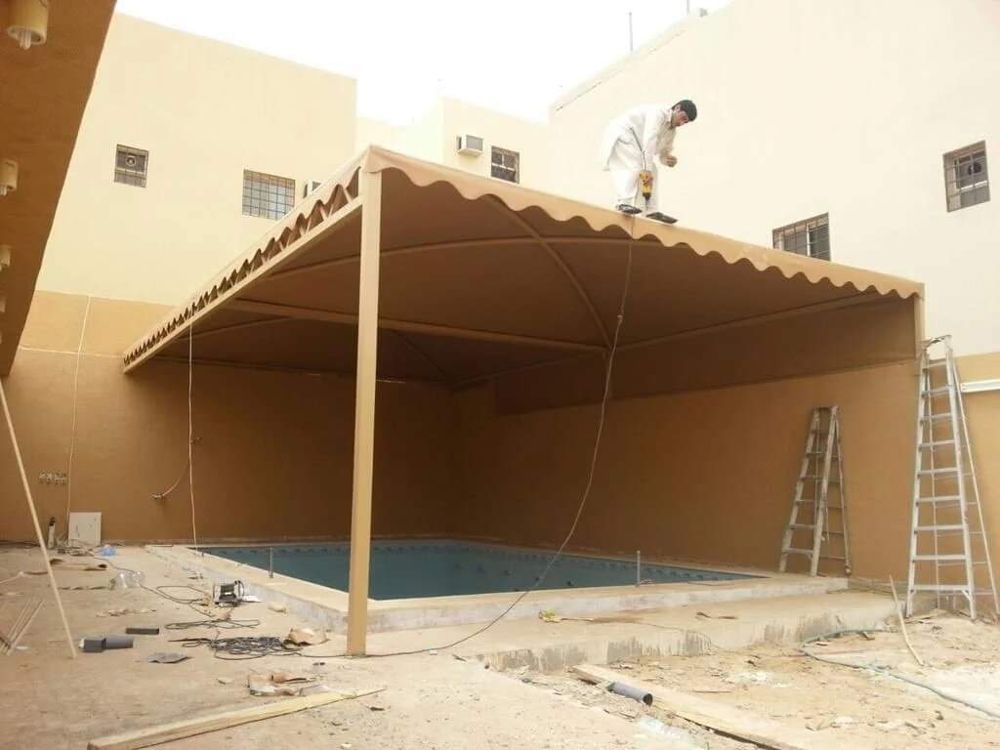 مظلة قماش كبيرة فوق مسبح في حوش منزل